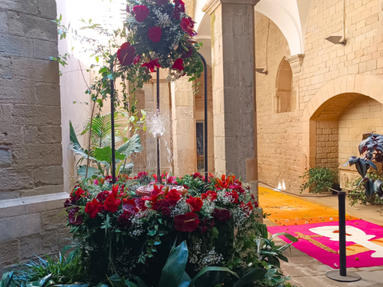 Una font decorada amb flors blanques i vermelles amb un ou sobre un brollador d'aigua.