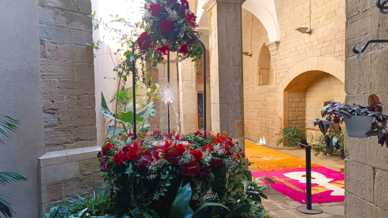 Una font decorada amb flors blanques i vermelles amb un ou sobre un brollador d'aigua.